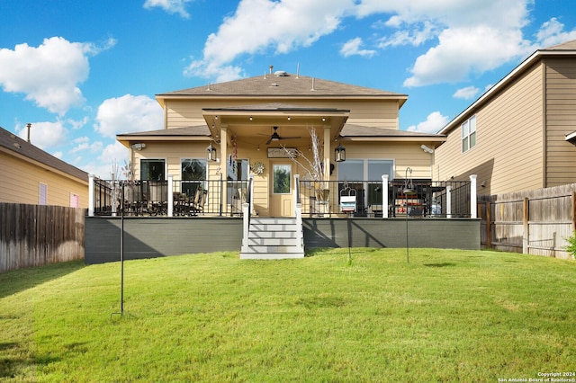 rear view of property featuring a lawn and ceiling fan