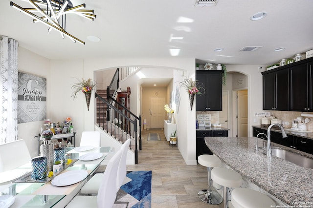 kitchen with light stone countertops, decorative backsplash, and sink