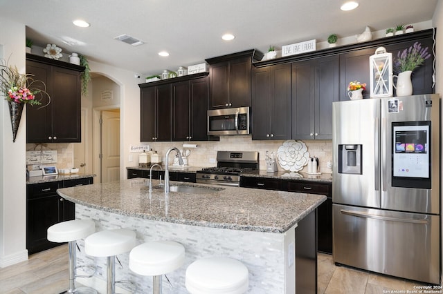 kitchen featuring dark brown cabinets, an island with sink, stainless steel appliances, and sink