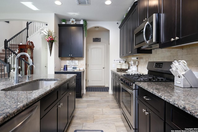 kitchen with tasteful backsplash, sink, dark stone counters, and appliances with stainless steel finishes