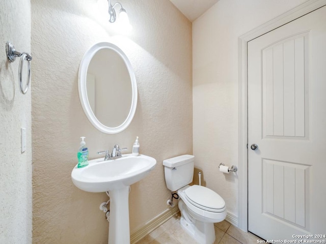 bathroom with tile patterned flooring, toilet, and a textured wall