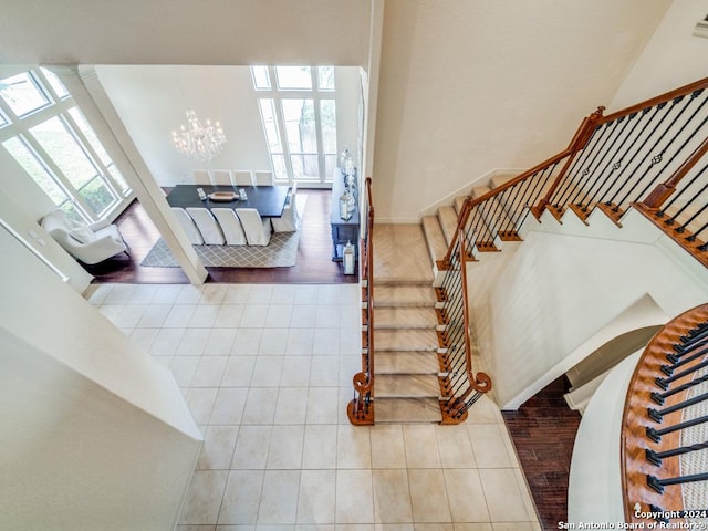 stairs with tile patterned flooring and an inviting chandelier