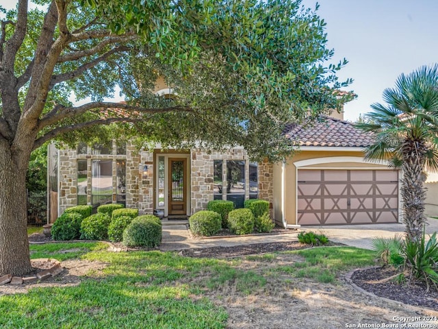 view of property hidden behind natural elements with concrete driveway, a tiled roof, an attached garage, and stucco siding