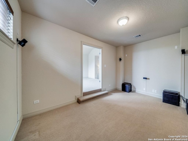 unfurnished room featuring baseboards, visible vents, carpet floors, and a textured ceiling