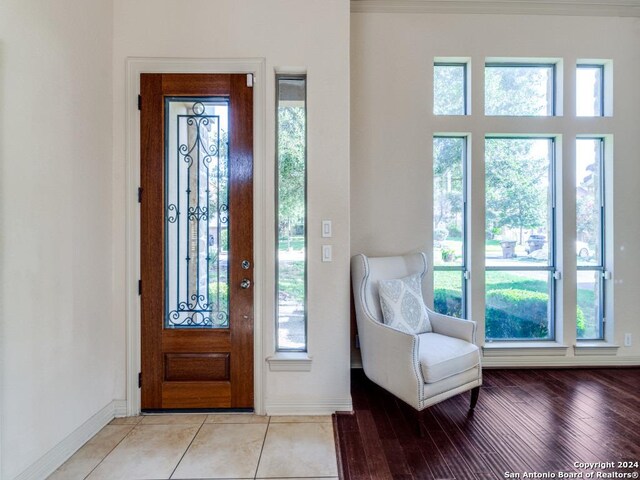 entrance foyer with a high ceiling, crown molding, hardwood / wood-style floors, an inviting chandelier, and decorative columns