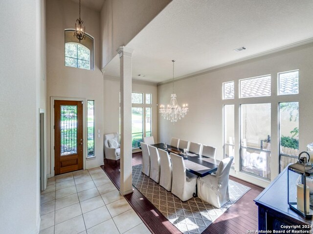 tiled dining room with an inviting chandelier, ornamental molding, and a towering ceiling