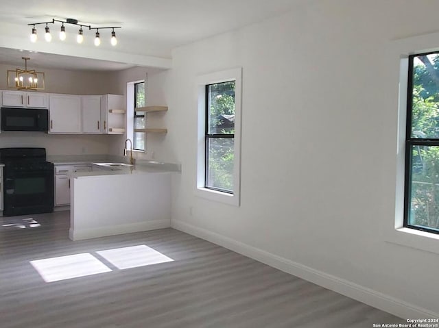 kitchen with hanging light fixtures, white cabinetry, plenty of natural light, and black appliances