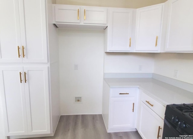 kitchen with white cabinetry, wood-type flooring, and stove