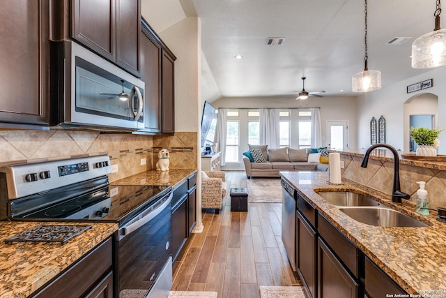 kitchen with dark brown cabinetry, light stone countertops, sink, tasteful backsplash, and appliances with stainless steel finishes