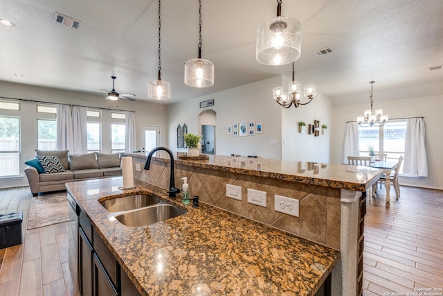 kitchen featuring a center island with sink, sink, and hanging light fixtures