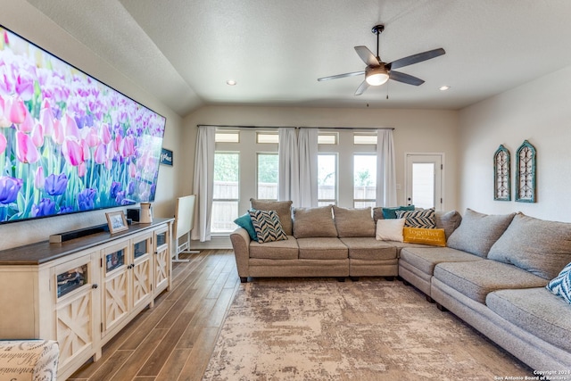 living room with a textured ceiling, ceiling fan, and lofted ceiling