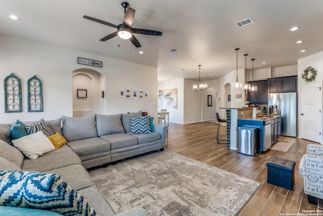 living room with ceiling fan with notable chandelier and sink