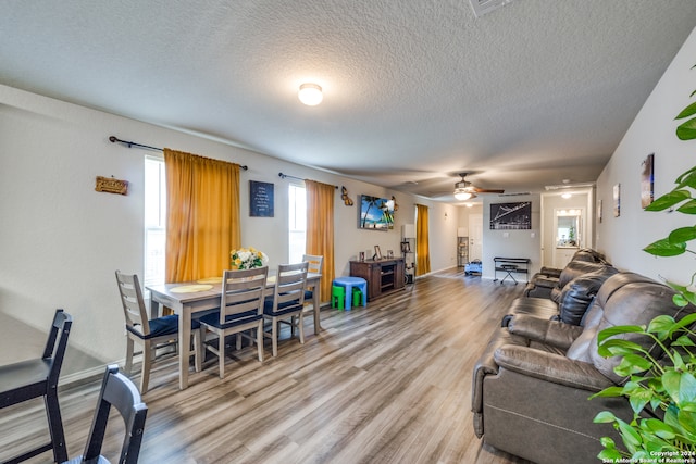 living room featuring a textured ceiling, wood-type flooring, and ceiling fan