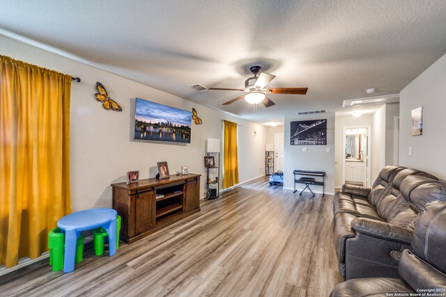 living room with a textured ceiling, hardwood / wood-style floors, and ceiling fan