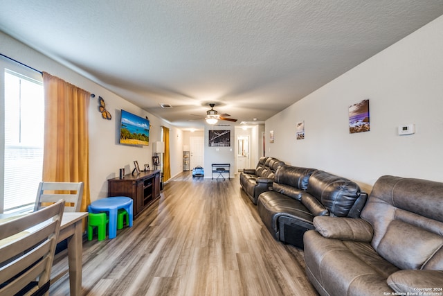 living room with hardwood / wood-style flooring, a textured ceiling, and ceiling fan