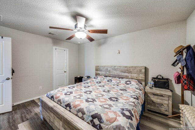 bedroom with dark hardwood / wood-style floors, a textured ceiling, and ceiling fan