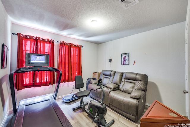 workout room featuring wood-type flooring and a textured ceiling