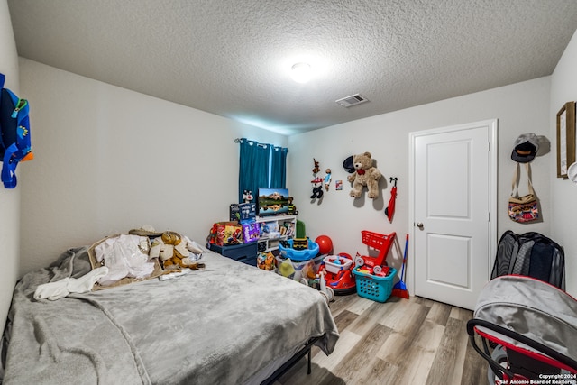 bedroom featuring light wood-type flooring and a textured ceiling