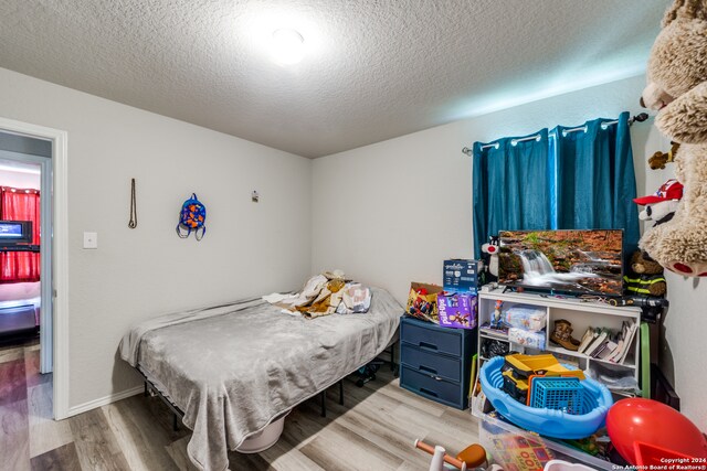 bedroom featuring hardwood / wood-style floors and a textured ceiling