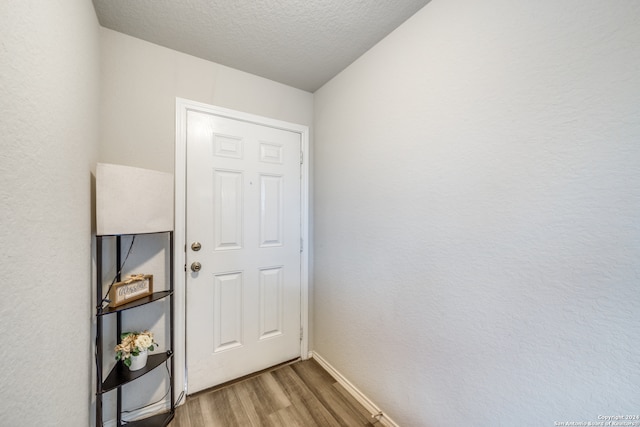 doorway with a textured ceiling and hardwood / wood-style floors