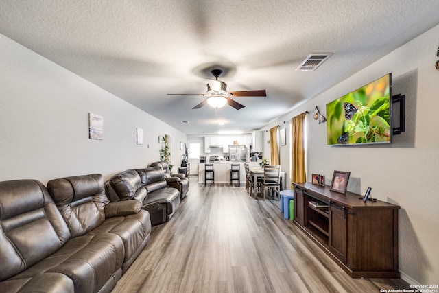 living room with hardwood / wood-style flooring, a textured ceiling, and ceiling fan