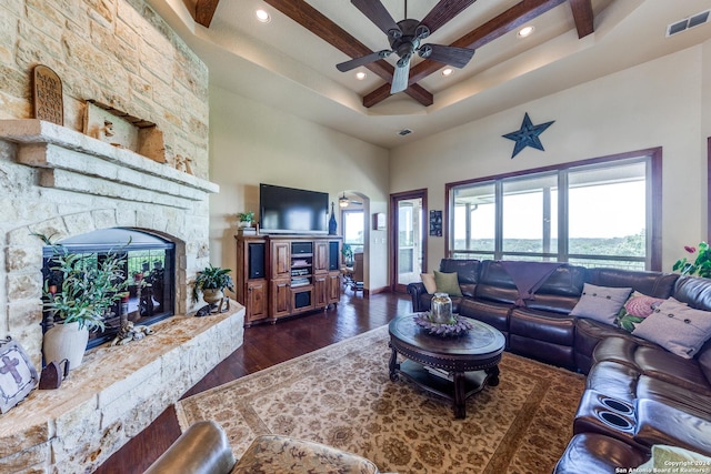 living room featuring dark hardwood / wood-style floors, ceiling fan, a towering ceiling, and a fireplace