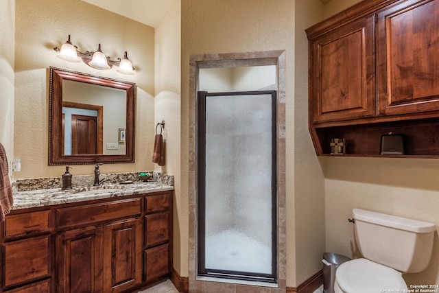 bathroom featuring vanity, toilet, and a shower with door