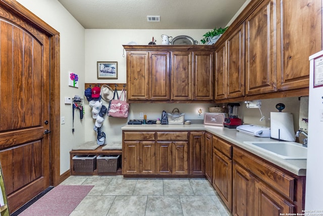 kitchen with light tile patterned floors, a textured ceiling, and sink