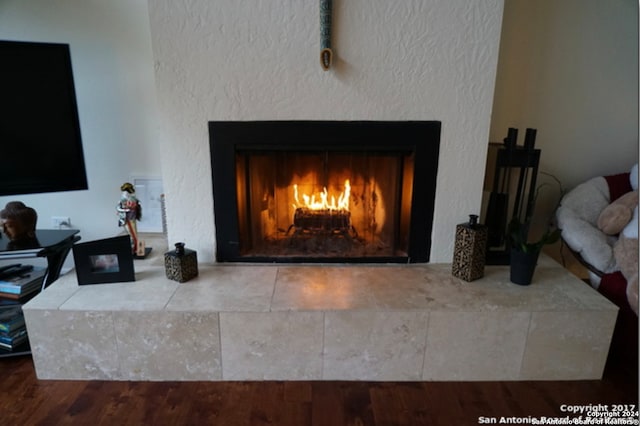 interior details featuring a tile fireplace and hardwood / wood-style flooring