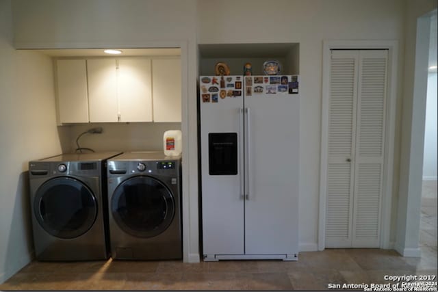 laundry room with tile patterned flooring, washer and clothes dryer, and cabinets