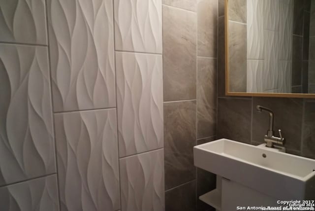 bathroom featuring sink and tile walls