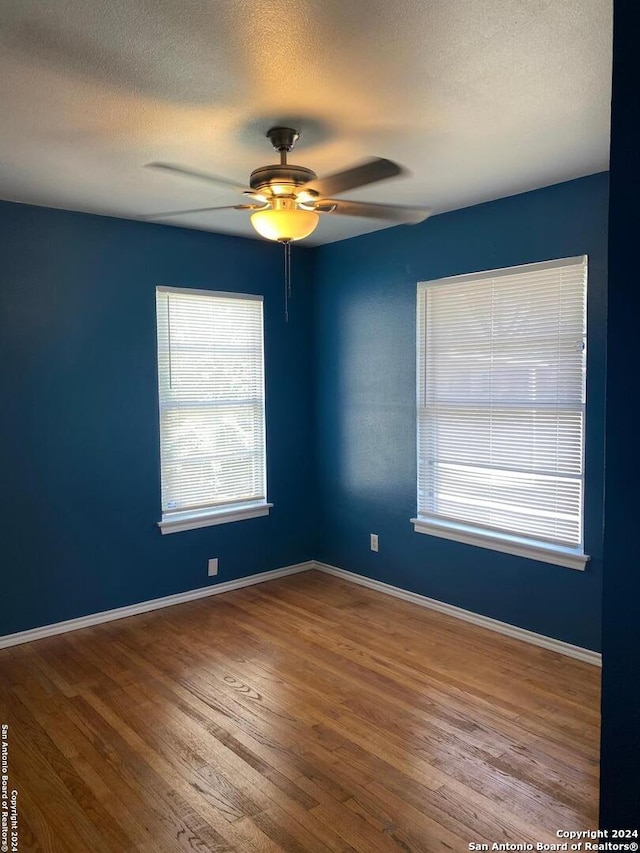 empty room featuring hardwood / wood-style floors, ceiling fan, and a textured ceiling