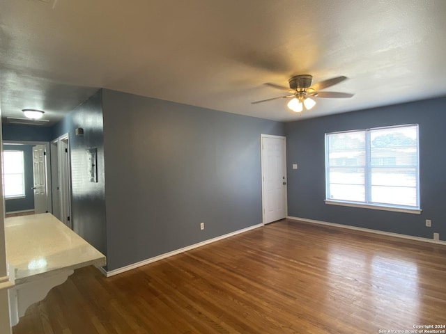 unfurnished room with ceiling fan, a healthy amount of sunlight, and dark hardwood / wood-style floors