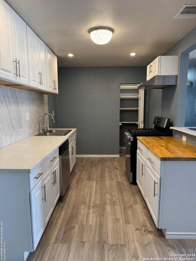 kitchen with wood counters, appliances with stainless steel finishes, sink, light hardwood / wood-style floors, and white cabinetry