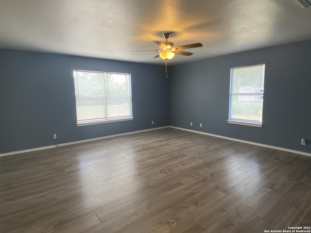 unfurnished room with a wealth of natural light, dark hardwood / wood-style flooring, and ceiling fan