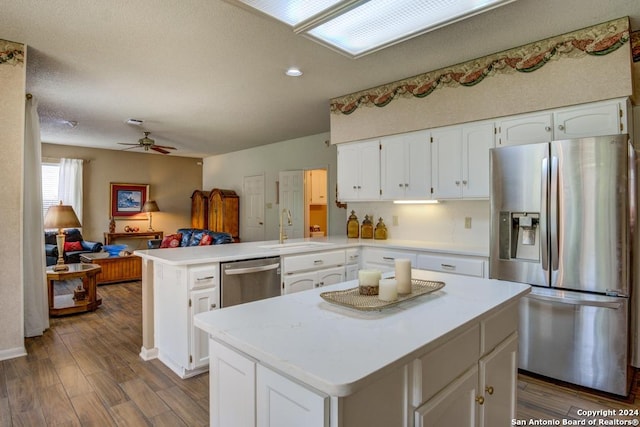 kitchen featuring white cabinetry, stainless steel appliances, a center island, and sink