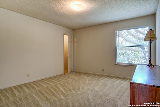 unfurnished room featuring carpet, a healthy amount of sunlight, and a textured ceiling