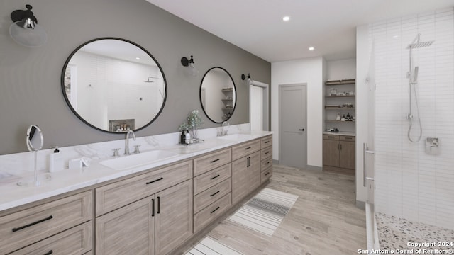 bathroom with tiled shower, hardwood / wood-style flooring, and dual vanity