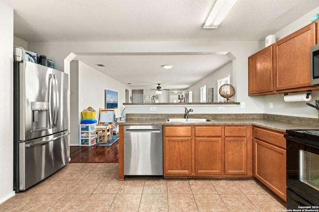 kitchen with light tile patterned flooring, appliances with stainless steel finishes, kitchen peninsula, and sink