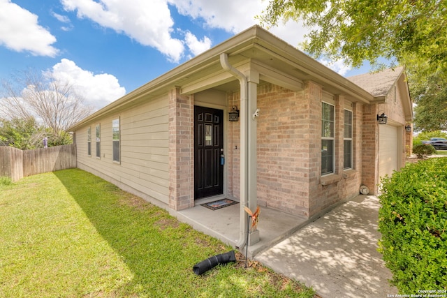 entrance to property with a garage and a lawn