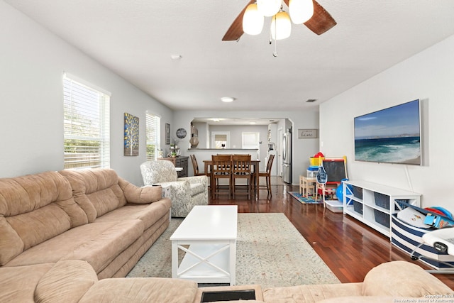 living room with dark wood-type flooring and ceiling fan