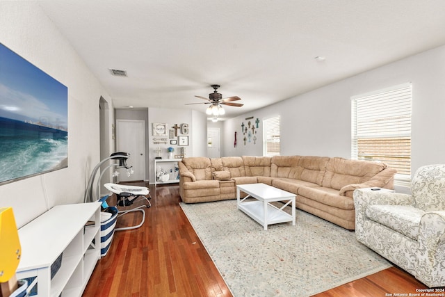 living room featuring dark wood-type flooring, ceiling fan, and a textured ceiling