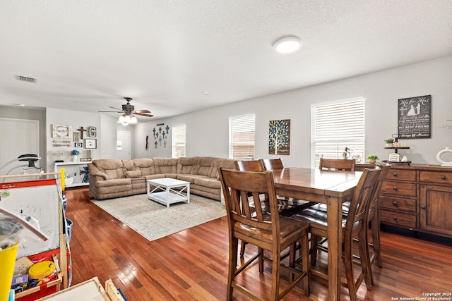 dining area with dark hardwood / wood-style floors, a textured ceiling, and a wealth of natural light