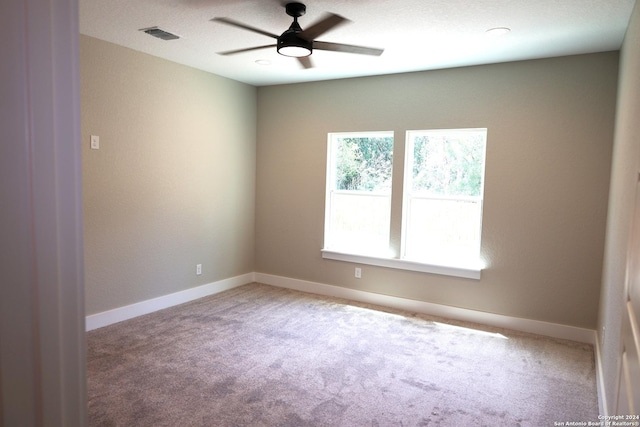 empty room with plenty of natural light, ceiling fan, and light colored carpet