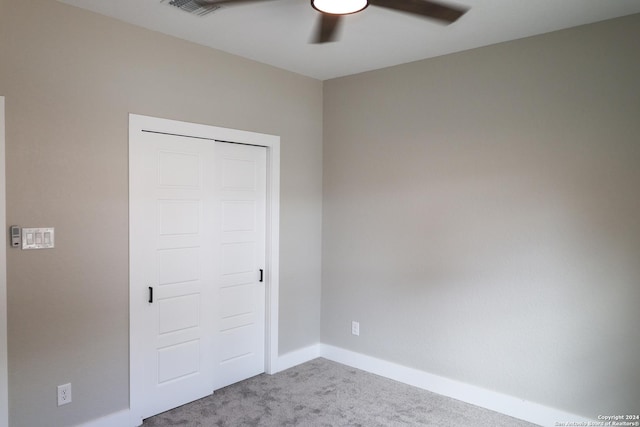 unfurnished bedroom featuring ceiling fan, a closet, and light carpet