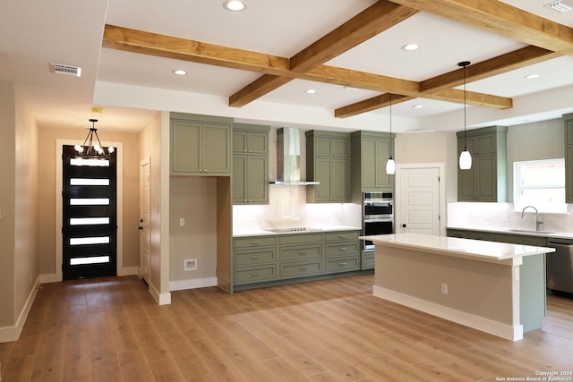 kitchen with appliances with stainless steel finishes, wall chimney exhaust hood, sink, pendant lighting, and green cabinets