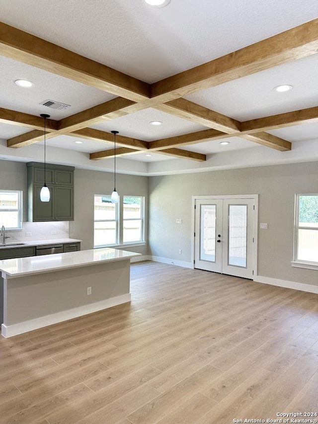 kitchen featuring pendant lighting, light wood-type flooring, a wealth of natural light, and coffered ceiling