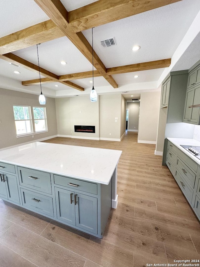 kitchen featuring decorative light fixtures, beam ceiling, light stone countertops, and coffered ceiling