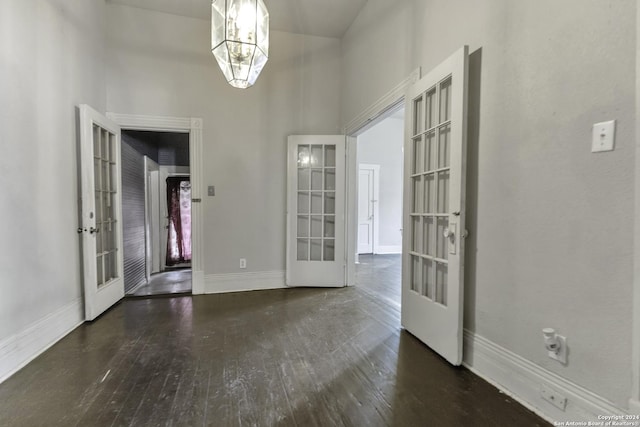 interior space with hardwood / wood-style flooring, a high ceiling, baseboards, and french doors