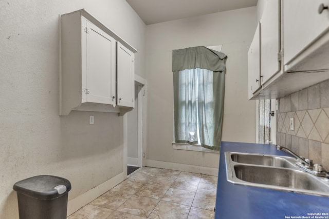 kitchen with white cabinets, sink, and tasteful backsplash